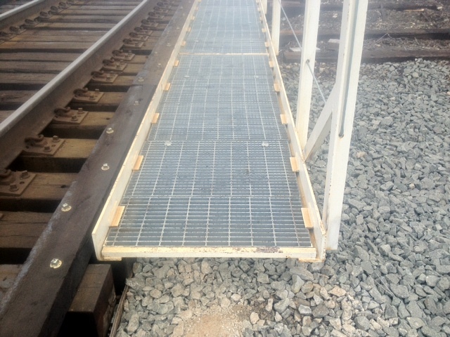 Bar grating bridge walkway installed between rail tracks
